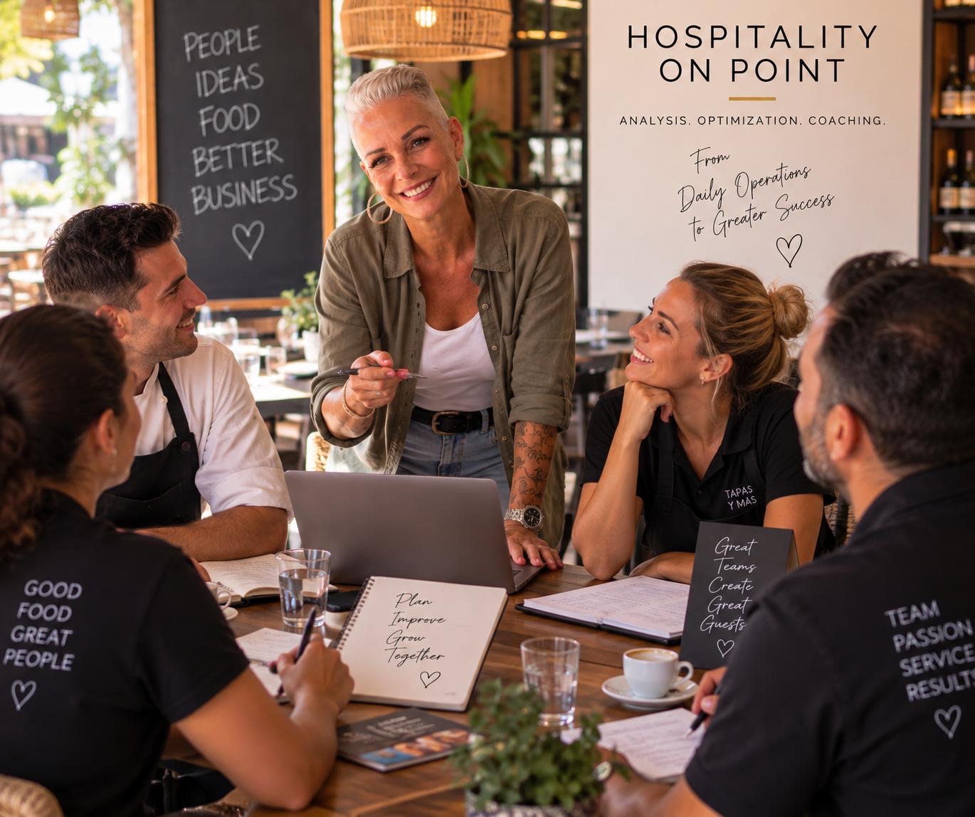 Renée Gorgoglione stands laughing with a pen in her hand at a table, surrounded by a chef in a white jacket and three staff members in black polo shirts, in a restaurant dining room.